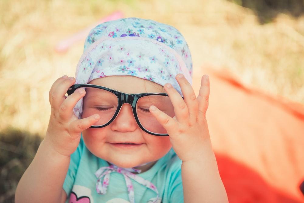 selective focus photography of baby wearing eyeglasses